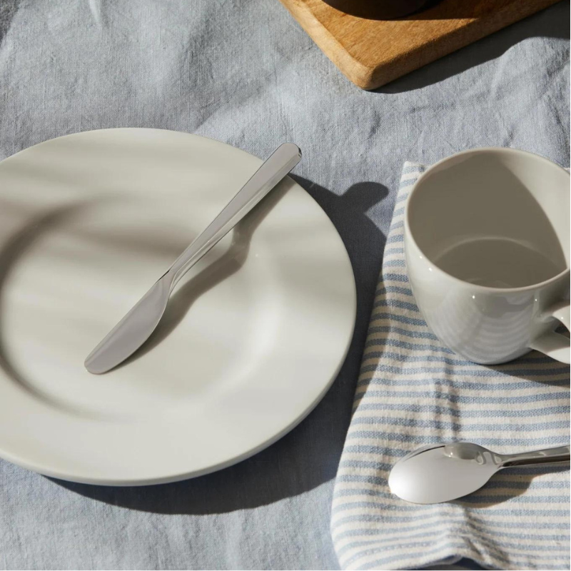 Alessi Amici Buttermesser auf weißem Teller auf gedecktem Tisch