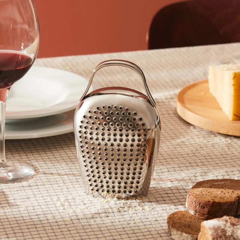 Alessi Käsereibe Cheese Please auf einem gedckten Tisch mit Rotwein, Parmesan und Brot