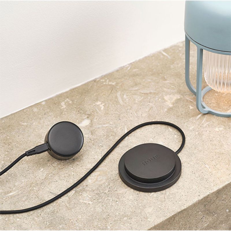 Magnetische Ladestation mit USB-Kabel für tragbare Outdoor-Leuchte von HAY, auf hellem Steinsockel
