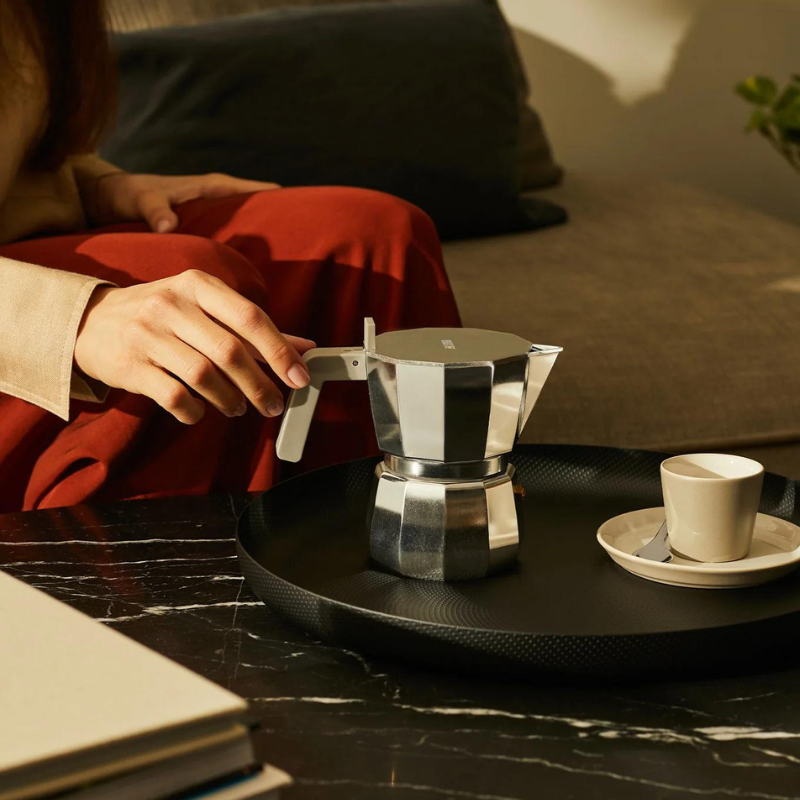 Espressokaffekanne aus Stahl auf einem Alessi Tablett, daneben eine Espressotasse