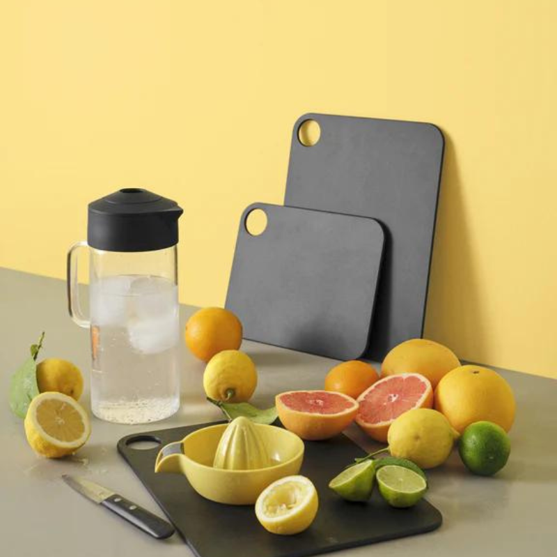 RIG TIG by Stelton Cut-It Schneidebrett mit einer Zitruspresse und einer Karaffe umgeben von vielen Zitronen und Orangen